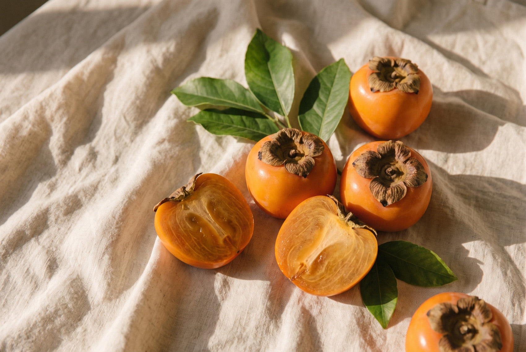 Ripe persimmons on cream linen